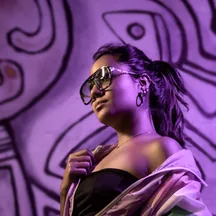 Model in sunglasses against a purple mural